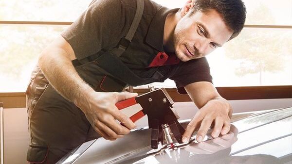 Techniker repariert Delle auf Motorhaube