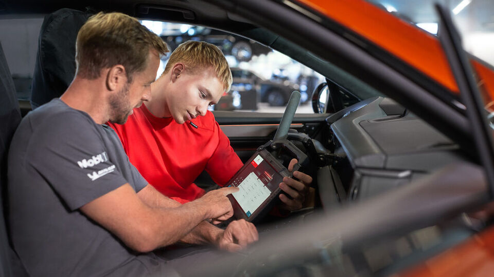 Zwei Mechaniker arbeiten an einem Porsche Fahrzeug