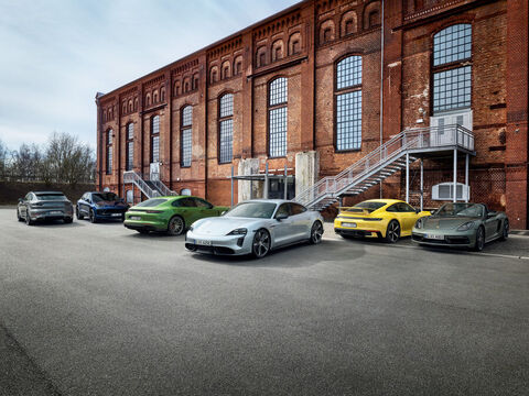 Verschiedene Porschemodelle vor einem Backsteingebäude