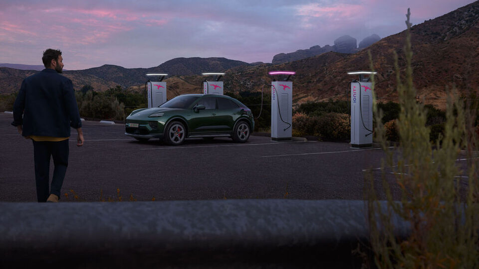 Ein Porsche Macan bei einer E-Ladestation bei Dämmerung
