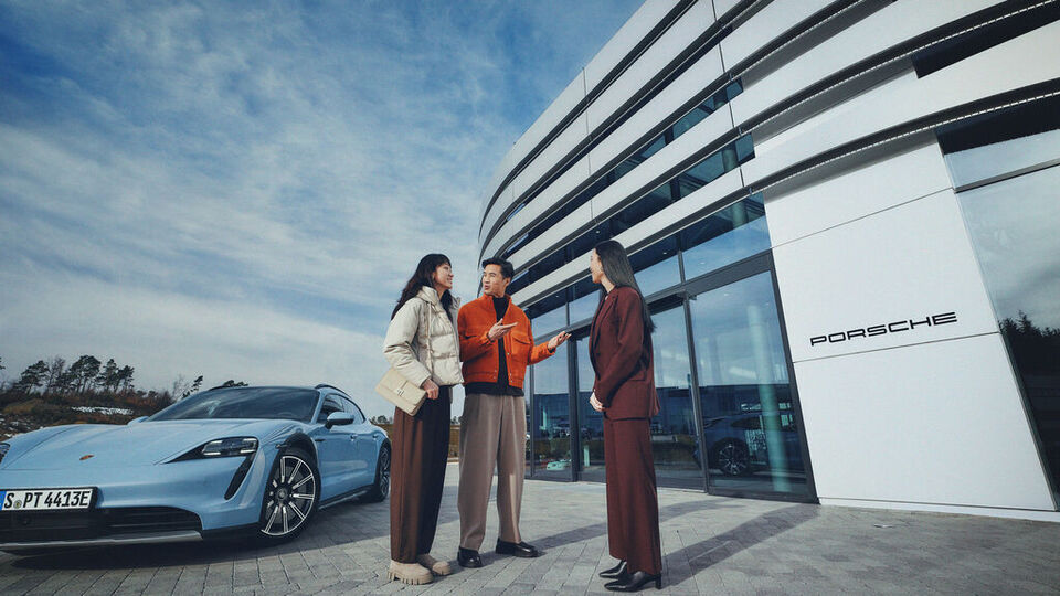 3 Menschen unterhalten sich vor einem Porsche Zentrum