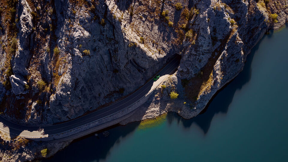 Küstenstraße von oben mit Porsche Fahrzeug