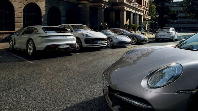 Verschiedene Porsche Modelle vor Haus