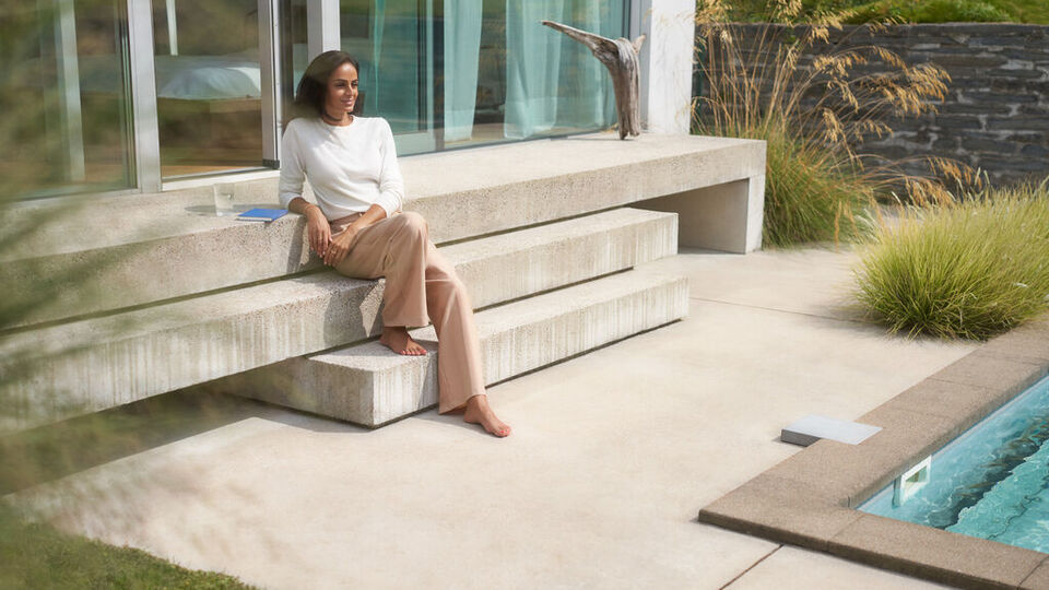 Mann sitzt entspannt auf einer Stufe neben einem Pool.