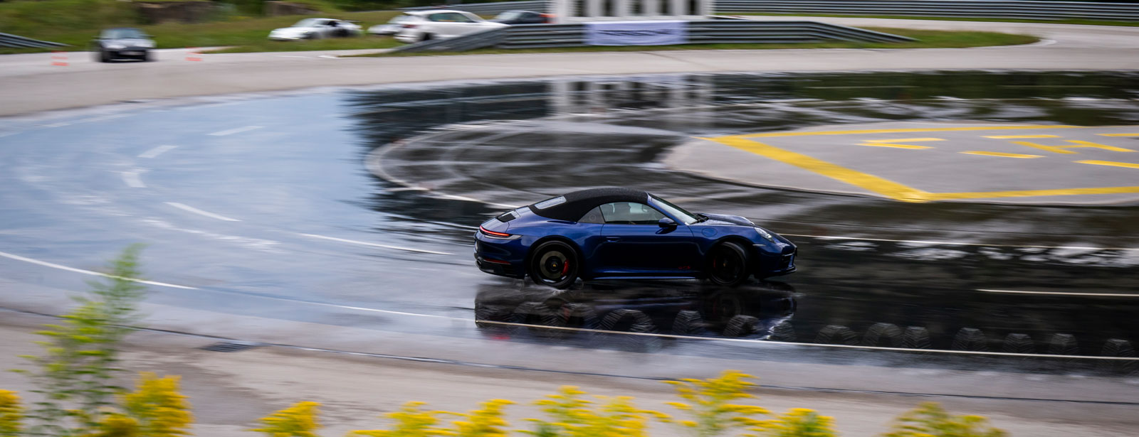 Porsche Boxter Cabrio driftet eine Kurve auf einer nassen Strasse