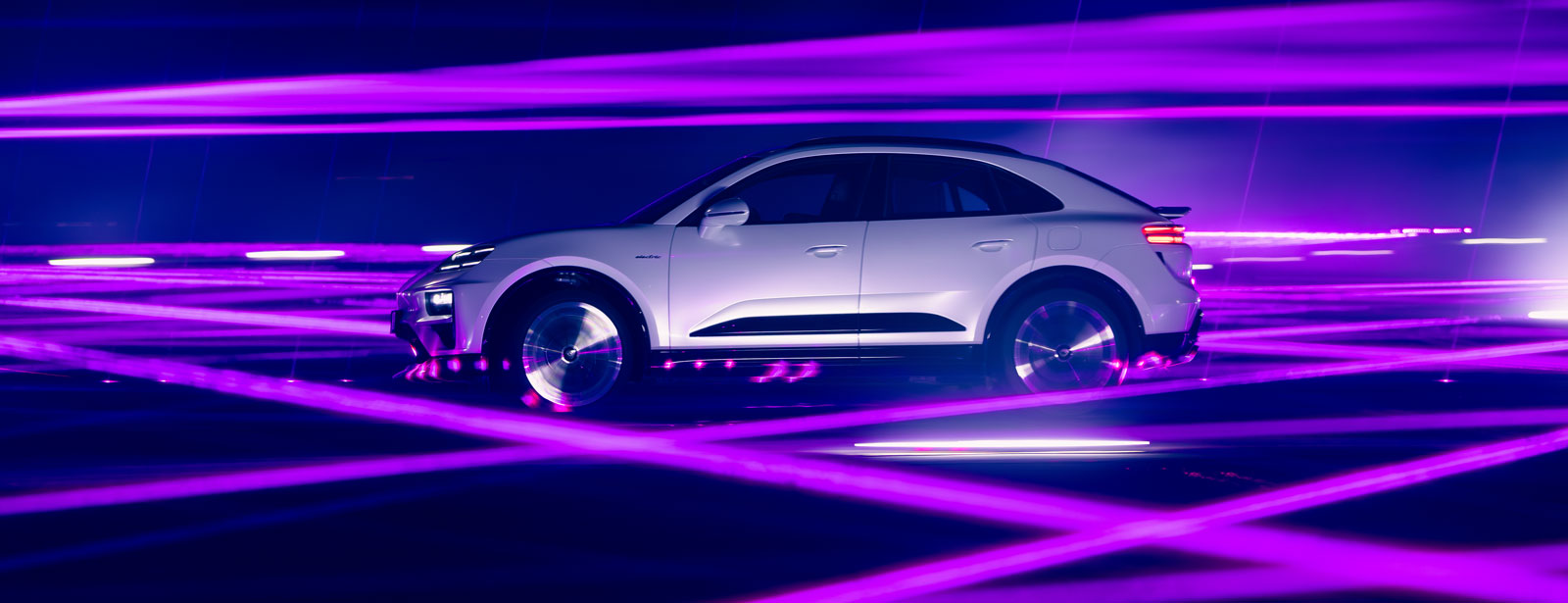 Seitliche Ansicht des Porsche Macan Turbo in Weiß, umgeben von lila Lichtlaserstrahlen