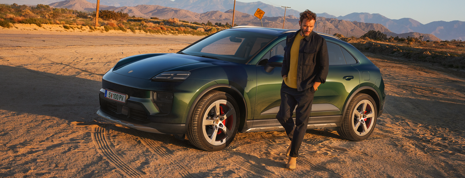 Grüner Macan 4S in seitlicher Ansicht auf sandigem Hintergrund