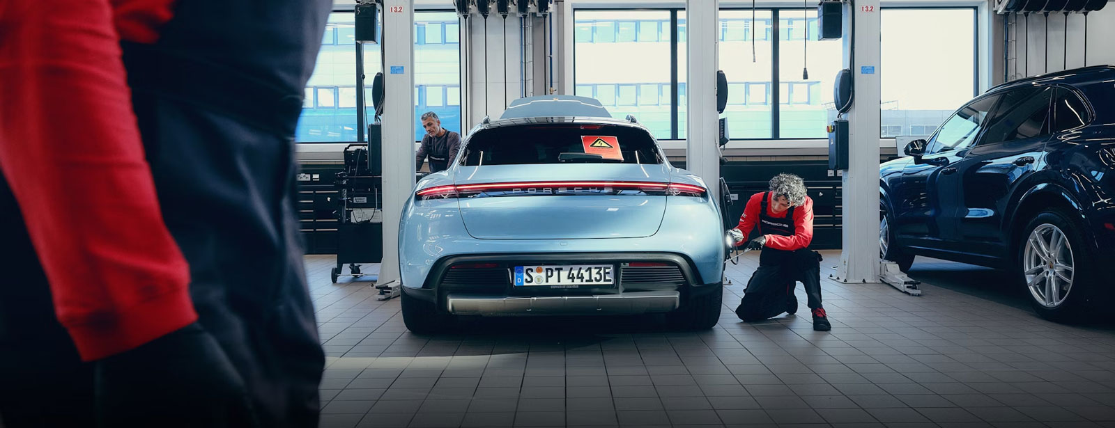 Technikerin arbeitet an einem Porsche Fahrzeug