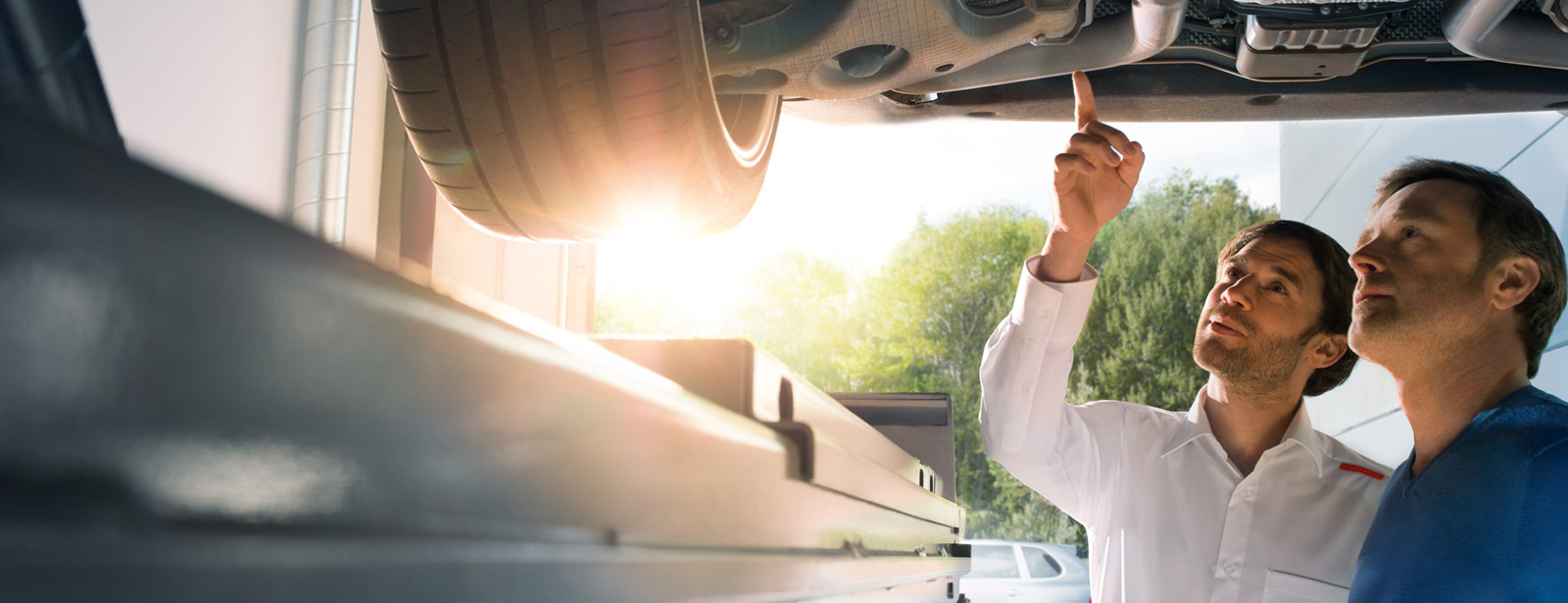 Zwei Männer begutachten ein Auto auf einer Hebebühne