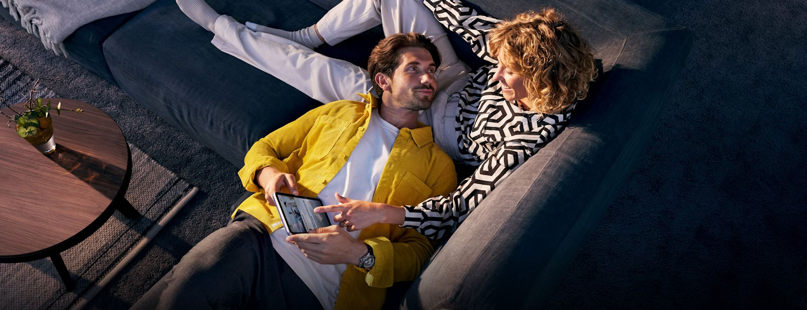 Paar liegt auf Couch und bedienen Tablet.